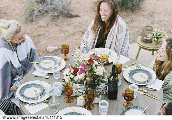 A small group of women enjoying an outdoor meal in a desert.