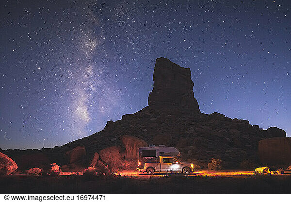 A small pickup RV is on a camping spot under the Milky Way
