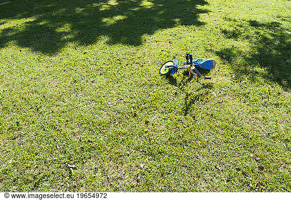 A small two wheeled decorated child's bicycle on its side on the grass.