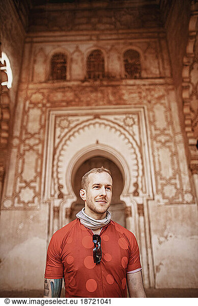 A smiling male caucasian tourist stands in Tinmel Mosque  Morocco