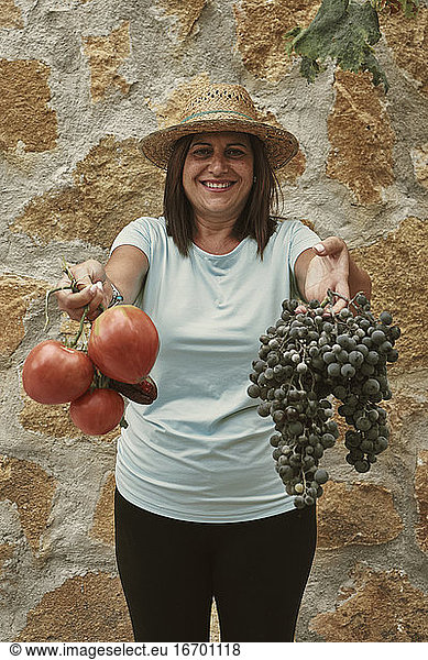 A smiling woman shows the products from her orchard
