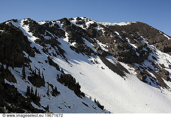 A snowy mountain range on with a blue sky above.