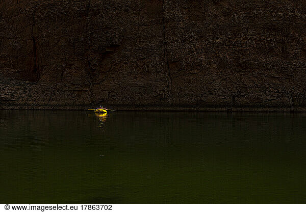 A solitary raft floating down a peaceful section of the Colorado river