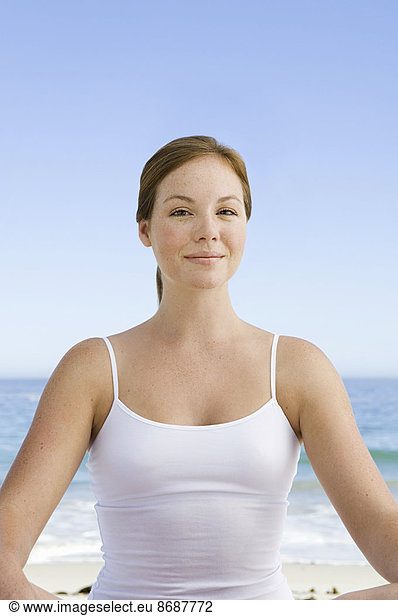 A spa treatment centre. A young woman seated in a relaxed pose on the beach.