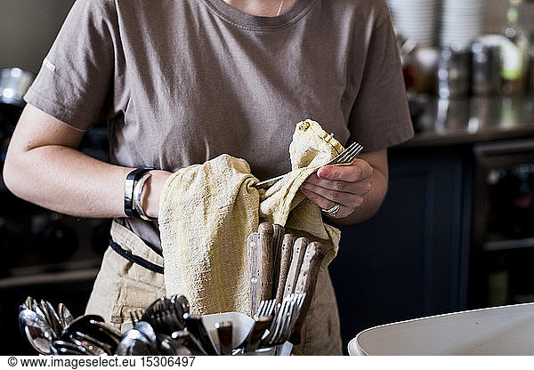 A staff member drying cutlery in a cafe.