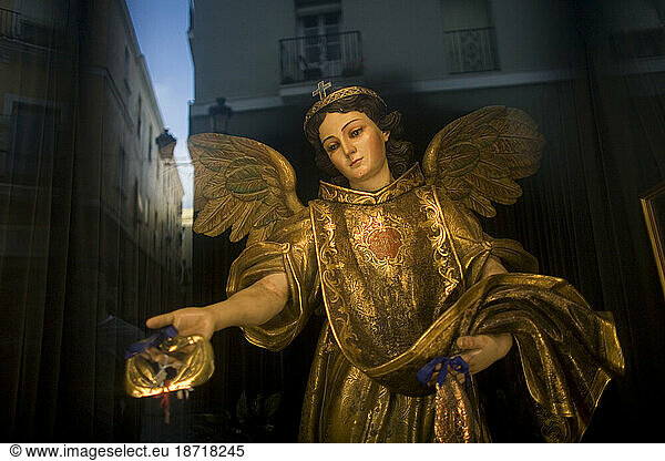A statue of Saint Raphael Arcangel sits behind a window as the city of Cadiz is reflected in Andalusia  Spain.