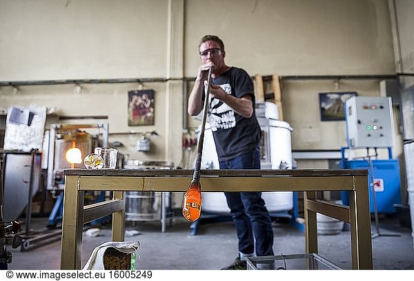 A student blowing glass during a glassblowing lesson at the Berlin Glas workshop in Wedding  Berlin  Germany.