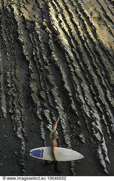 A surfer spots a point break after hiking across rocks in Santa Barbara  California.