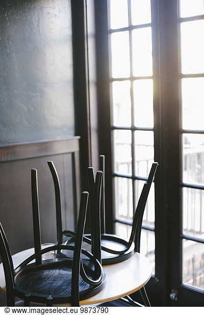 A table in a cafe with the chairs up  at the end of the day.