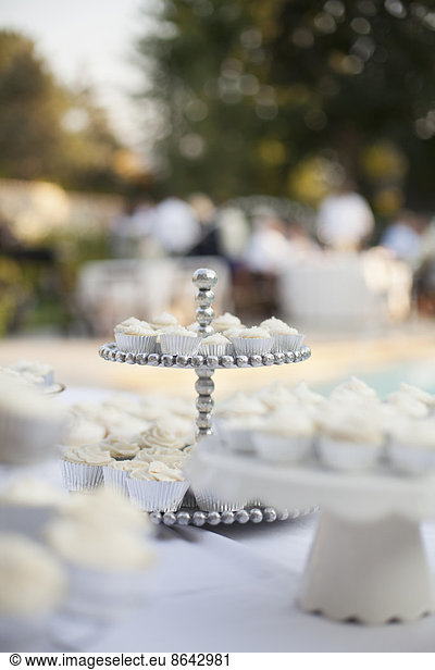 A table laid for a banquet or a wedding breakfast. White table cloth  cake stand  and table setting.
