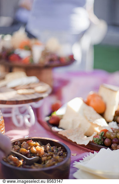 A table laid with a buffet selection of food dishes. Desserts and cheese board.