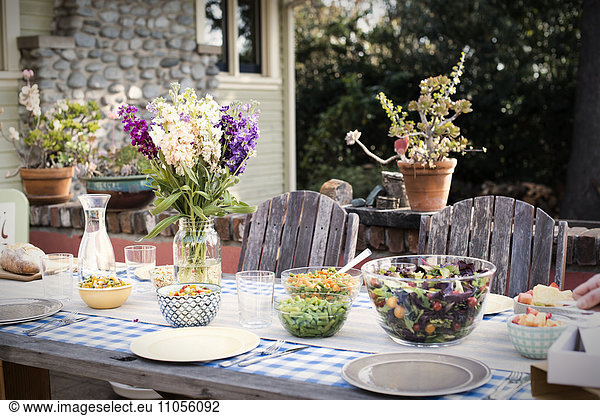 A table set for a meal outdoors in a garden.