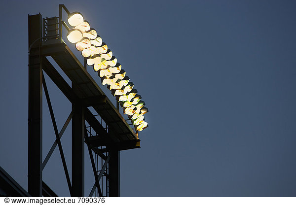 A tall lighting gantry or tower with strong powerful floodlights  over a sports area or stadium.