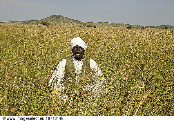 A Tanzanian man in traditional colonial era attire poses for a portrait on the Serengeti plain  Tanzania.
