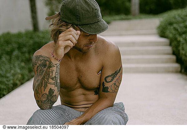 A tattooed man sits on the steps.