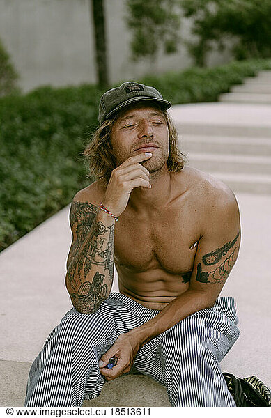 A tattooed man sits on the steps.