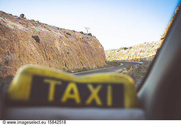 A taxi drives on the road between cliffs
