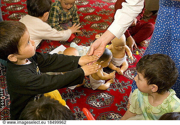 A teacher inspects a child's hands for cleanliness at a Kabul preschool.
