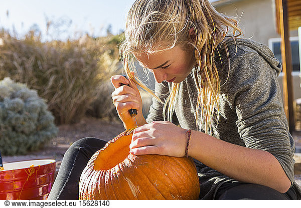 A teenage girl carving a pumpkin at Halloween