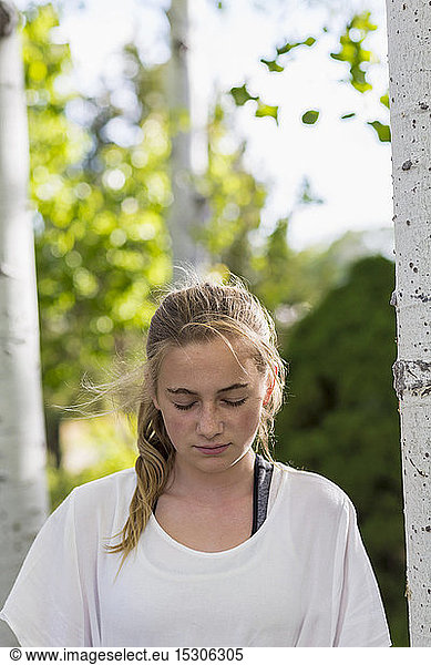 A teenage girl in a white dress among trees