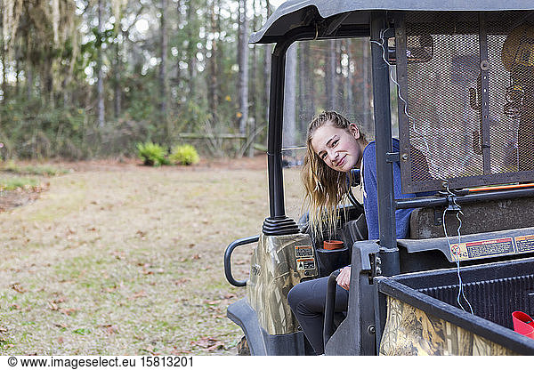 A teenage girl in an all terrain vehicle  a buggy  looking out.