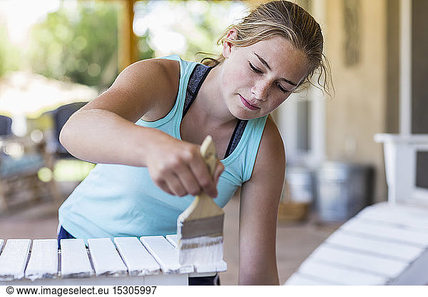 A teenage girl painting furniture white
