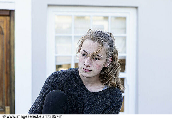 A teenage girl sitting outside a house  alone