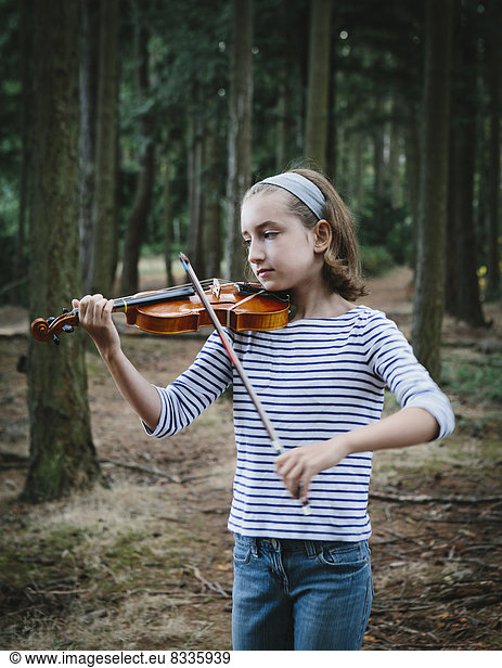 A ten year old girl playing the violin in Discovery Park  Seattle.