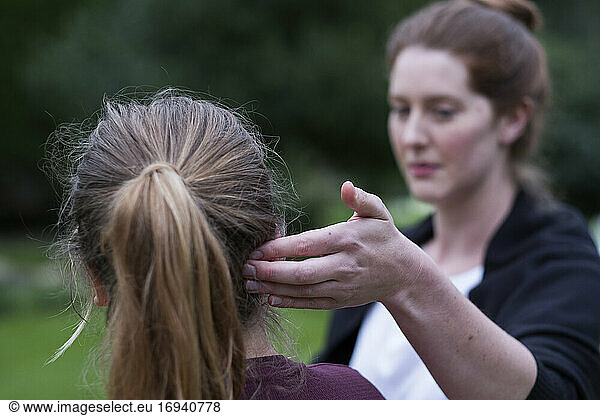 A therapist touching a client's head by her ear.