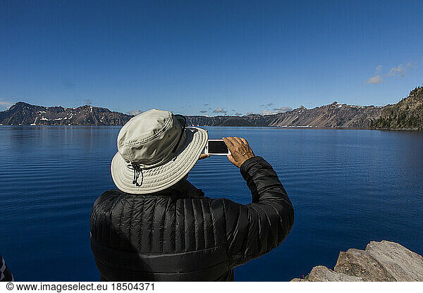 A tourist takes a photo of Crater Lake.