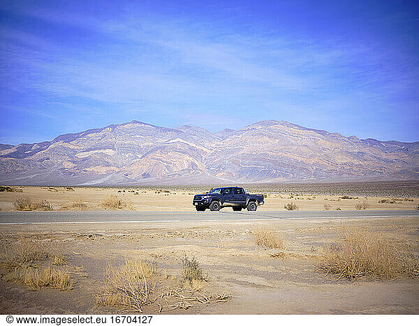 A toyota truck parked on the side of a desert highway  Death Valley.