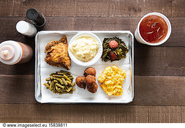 A tray of fried chicken  green beans  mac & cheese meal with sweet tea