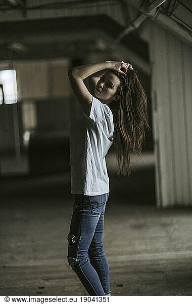 A twenty something female poses in an abandoned industrial building