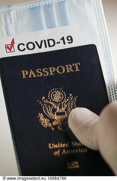 A US passport with a Covid-19 immunization document and a face mask.