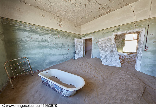 A view of a bathroom in a derelict building full of sand.
