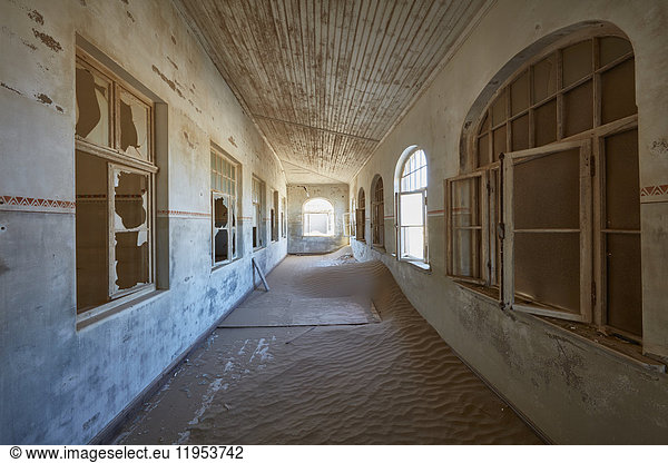 A view of a corridor in a derelict building full of sand.