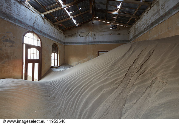 A view of a room in a derelict building full of sand.