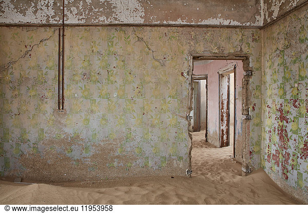 A view of a room in a derelict building full of sand.