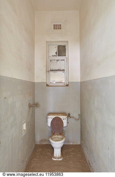 A view of a toilet in an abandoned derelict building full of sand.