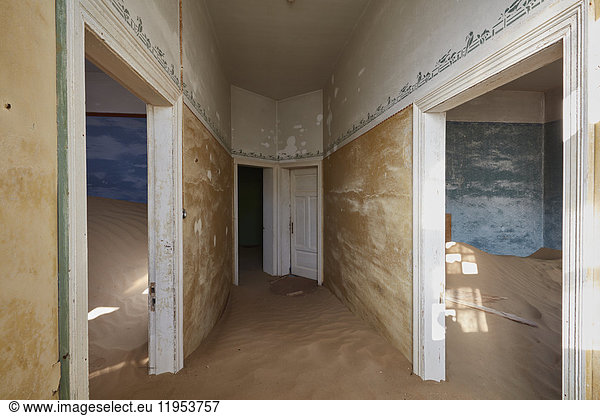 A view of rooms in a derelict building full of sand.