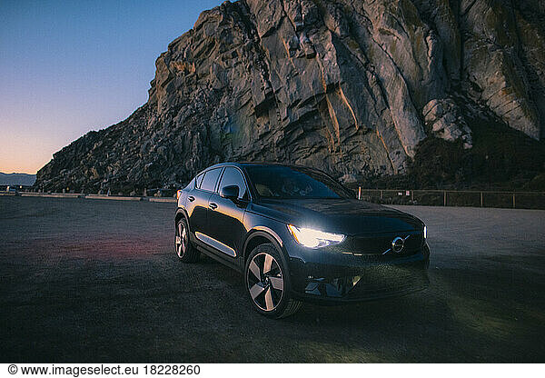 A Volvo C40 - an electric car - parks next to a large rock.