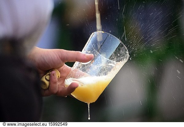 A waiter pours cider into a glass in the Requexo neighborhood  Mieres  Asturias  Spain
