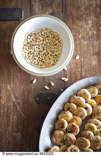 A white pottery bowl  full of dried corn kernels. A dish of baked pastries.