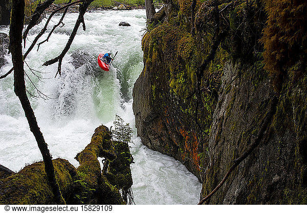 A white water kayaker paddles over a waterfall on the Cheakamus River.