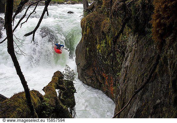 A white water kayaker paddles over a waterfall on the Cheakamus River