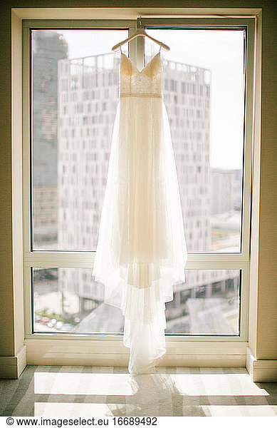 A white wedding dress hanged on the hanger.