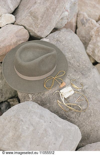 A wide brimmed hat and jewellery  personal belongings left on a rock.