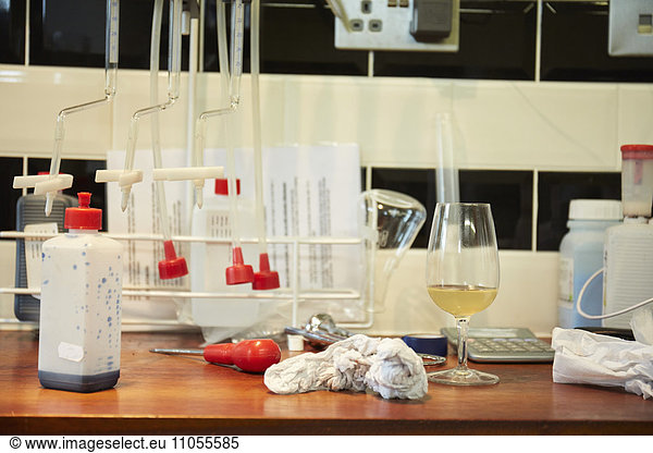 A winery laboratory. A worktop with flasks and tubes  a glass of wine and a screwdriver.