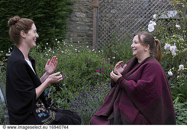 A woman and a therapist talking in a garden.