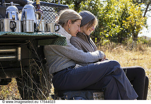 A woman and her teenage daughter sitting by a jeep